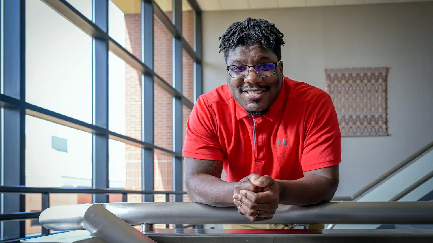NC State staffer, Bredell Moody, smiles into the camera with his hands clasped together.