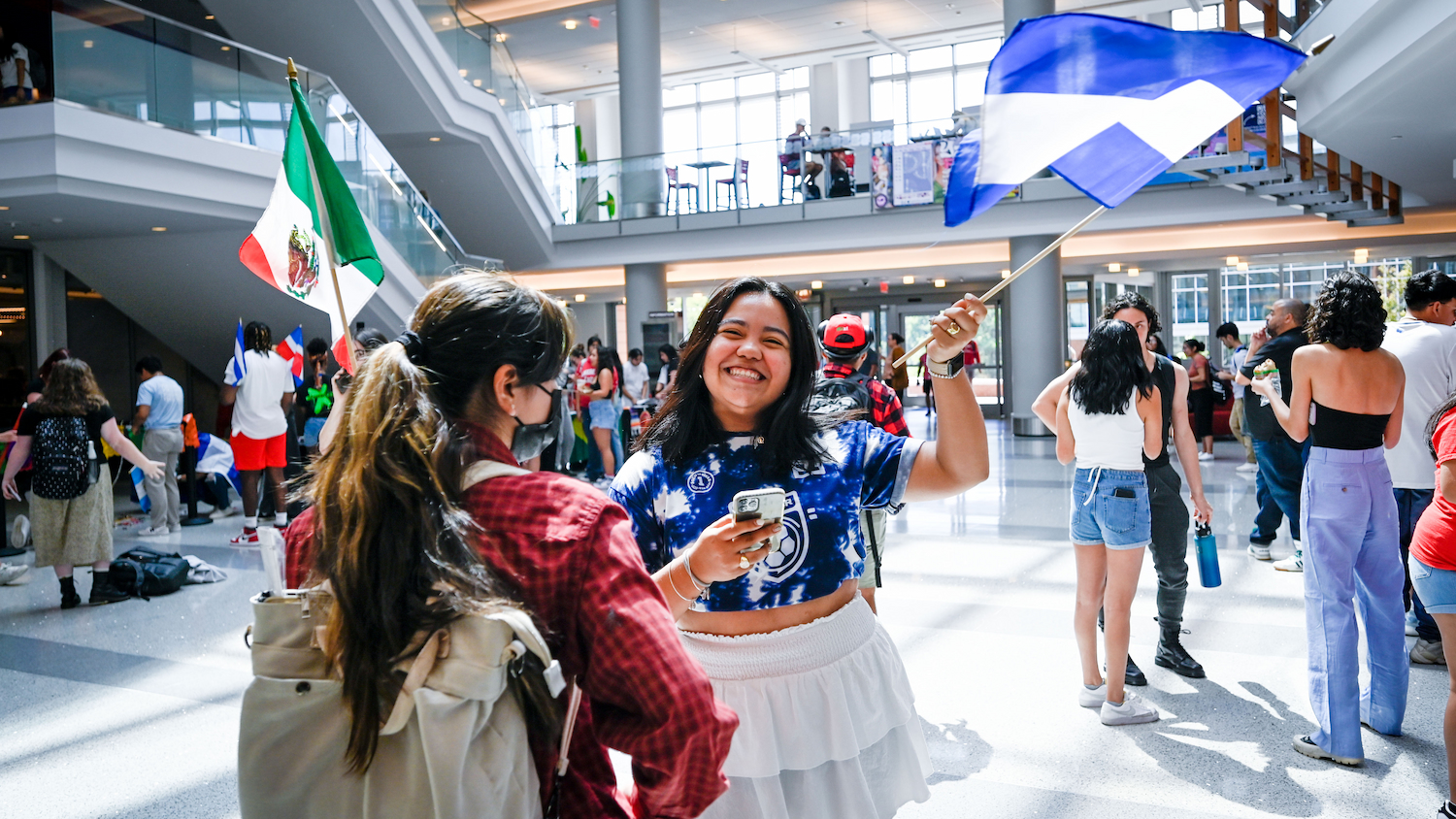 An NC&#160;State students smiles and waves a Nicaraguan flag in the Talley Student Union during Latinx Heritage Month.